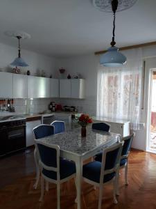 une cuisine avec une table et des chaises bleues et une cuisine avec des armoires blanches dans l'établissement Vila Elena, à Kikinda