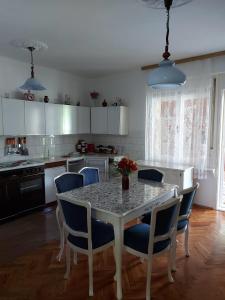 une cuisine avec une table et des chaises et une cuisine avec des placards blancs dans l'établissement Vila Elena, à Kikinda