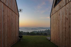 uma vista entre dois celeiros de um campo com o pôr-do-sol em Widokowe Stodoły Bieszczady em Lesko