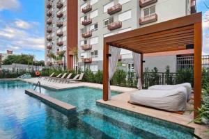 a hotel with a bed and a swimming pool at Elegance PUC in Porto Alegre