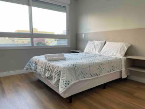 1 dormitorio con cama y ventana grande en Elegance PUC, en Porto Alegre