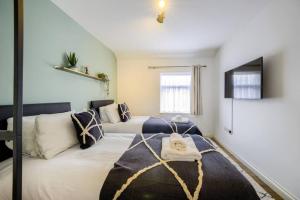 考文垂的住宿－LOW rate for a 4-Bedroom House in Coventry with Free Unlimited Wi-fi 2 Car Parking 53 QMC，一间卧室配有两张床和电视。