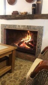 a fire in a fireplace with two chairs and a table at Cortijo Abril in Priego de Córdoba