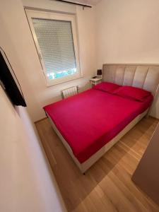 a bedroom with a large red bed with a window at Apartman Madagaskar in Banja Luka