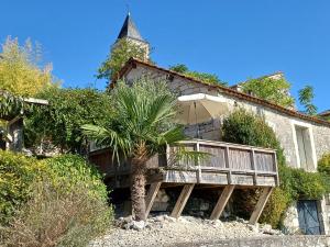 une maison avec une terrasse en bois et un parasol dans l'établissement Les Terrasses de Flaugnac, à Flaugnac