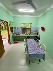 ein Esszimmer mit einem lila Tisch und Stühlen in der Unterkunft Rumah Comel in Kampung Degong