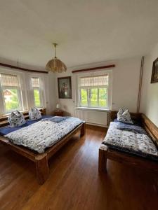 2 łóżka w pokoju z drewnianymi podłogami i oknami w obiekcie Vila Kučera w mieście Chřibská