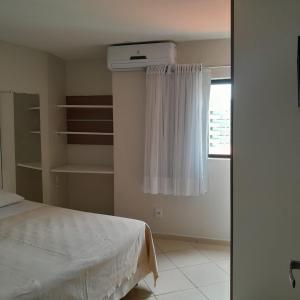 1 dormitorio con cama blanca y ventana en Akropolis Home, en João Pessoa