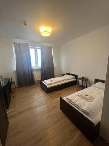 two beds in a room with wooden floors and a window at CASILINO Hotel A 20 Wismar in Wismar