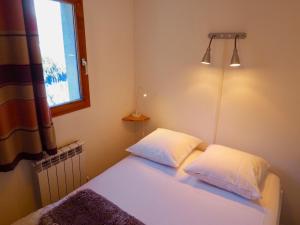 ein Schlafzimmer mit einem Bett mit zwei Kissen und einem Fenster in der Unterkunft Appartement Valfréjus, 4 pièces, 8 personnes - FR-1-468-34 in Valfréjus