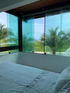 um quarto com uma grande janela com palmeiras em Casa no Paraíso dos Carneiros em Tamandaré em Tamandaré