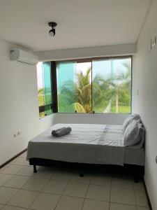 een groot bed in een kamer met een groot raam bij Casa no Paraíso dos Carneiros em Tamandaré in Tamandaré