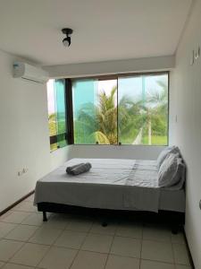 Una cama grande en una habitación con una ventana grande. en Casa no Paraíso dos Carneiros em Tamandaré, en Tamandaré