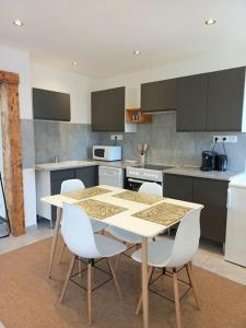 a kitchen with a table and white chairs at Appartement Les Géraniums in Remiremont