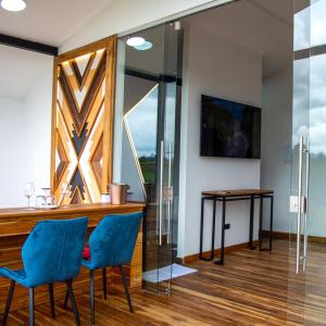 un bar con sillas azules en una habitación con ventana en Örök Hotel, en Rionegro