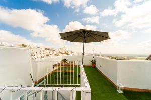 a balcony with an umbrella and a table and chairs at Casa La Fontana 1 in Vejer de la Frontera
