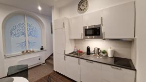una cocina con armarios blancos y un reloj en una ventana en Red Lion Pub & Apartments Szentendre, en Szentendre