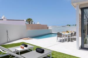 a patio with a table and chairs and a swimming pool at KARAT Villa Neveda in Adeje