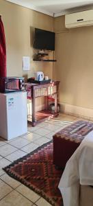 um quarto com uma televisão, uma mesa e um frigorífico em Mthandi Wokuhamba Lodge em Dundee