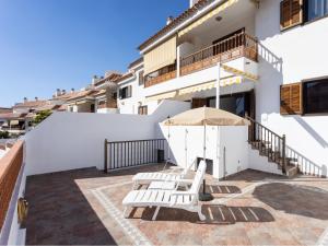 a patio with two white chairs and an umbrella at Live cardon las americas con piscina y terraza in Arona