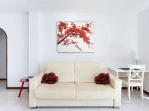 a living room with a white couch with red leaves on a tree at Live cardon las americas con piscina y terraza in Arona