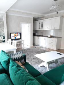 ein Wohnzimmer mit einem grünen Sofa und einem weißen Tisch in der Unterkunft Comfortable apartment in Bischkek