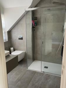 a bathroom with a glass shower with a toilet and a sink at LymingtonBnB in Lymington