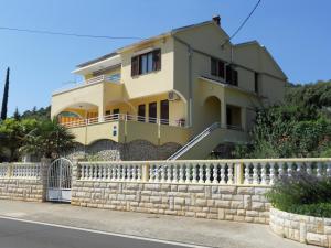 a yellow house behind a stone fence at Apartments Gržanov in Sutomišćica