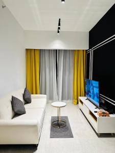 sala de estar con sofá blanco y TV en KLCC Suites At Axon Residence en Kuala Lumpur