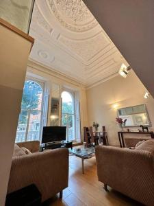 sala de estar con techo artesonado, sofá y mesa en Grade II Listed Balconied 3-Bed Mezzanine Kensington Flat, en Londres