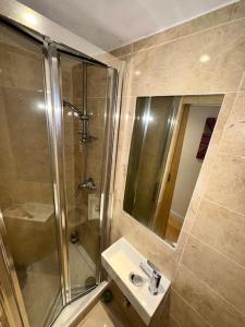 y baño con ducha, lavabo y espejo. en Grade II Listed Balconied 3-Bed Mezzanine Kensington Flat, en Londres