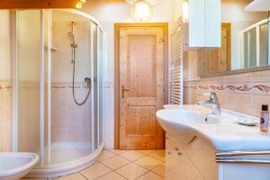 uma casa de banho com 2 lavatórios e um chuveiro em Cuore delle Dolomiti em Tonadico