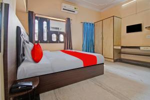 1 dormitorio con cama con almohadas rojas y escritorio en Flagship Hotel Elite Inn, en Jaipur