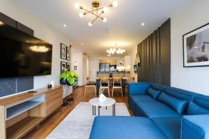 uma sala de estar com um sofá azul e uma televisão em Alcanfores by Wynwood House em Lima