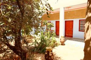 una casa con una porta rossa e un albero di gîte d'étape ziz oasis a Achbarou