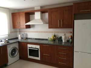 a kitchen with wooden cabinets and a white refrigerator at La Galera Park House in Estepona