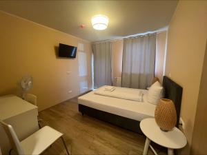 Schlafzimmer mit einem Bett, einem TV und einem Stuhl in der Unterkunft CASILINO Hotel A 20 Wismar in Wismar