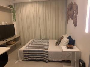 a small bedroom with a bed and a television at Lindo e bem localizado in Porto De Galinhas +46 photos