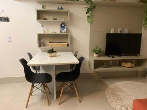 einen Tisch und Stühle im Wohnzimmer mit TV in der Unterkunft Lindo e bem localizado in Porto De Galinhas