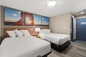 a hotel room with two beds and paintings on the wall at Days-Inn by Wyndham Albuquerque I-25 in Albuquerque
