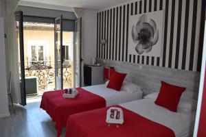 Dos camas en una habitación de hotel con rojo y blanco en Hostal Madrid Sol, en Madrid