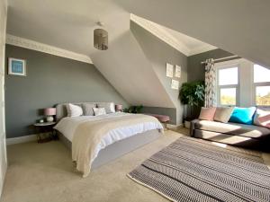 a attic bedroom with a bed and a couch at Stunning Sea View Home 2 Minutes Walk to the Beach in Bournemouth