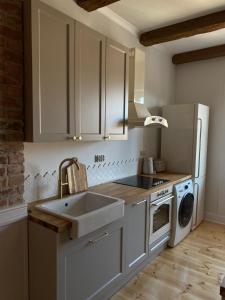 a kitchen with white cabinets and a sink and a dishwasher at Apartments PSD Anny Łajming 3A in Słupsk
