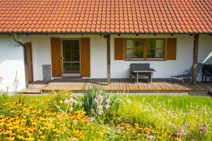 una casa con techo naranja y un jardín con flores en Ferienwohnung Bayerwaldblick Hexental, en Bogen