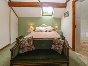The Cottage at Ty Newydd في لانفيربولوغووِنشِل: غرفة نوم بسرير واريكة خضراء