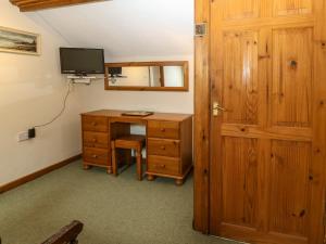 The Cottage at Ty Newydd في لانفيربولوغووِنشِل: غرفة بها مكتب وتلفزيون وباب