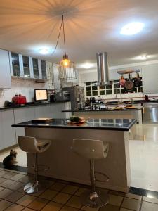 cocina con barra y 2 taburetes en Quarto Aconchegante Em Uma Linda Casa, en Brasilia