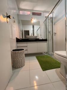 Baño blanco con lavabo y espejo en Quarto Aconchegante Em Uma Linda Casa, en Brasilia