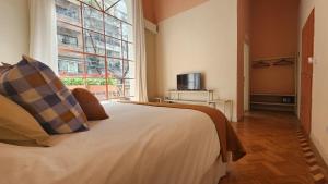 ein Schlafzimmer mit einem Bett und einem großen Fenster in der Unterkunft Casa Par Grand Suites in Buenos Aires