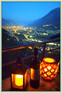una botella de vino y velas en una mesa con vistas en Atmosfera e vista mozzafiato Chalets en Aosta